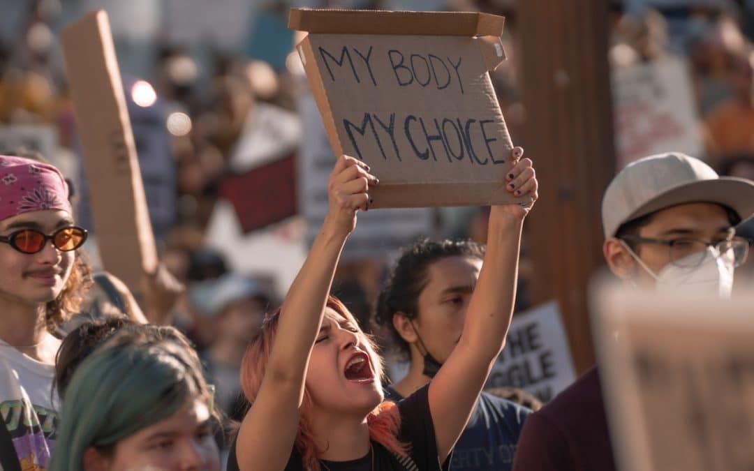 Young person at an abortion rights protest holding a My Body My Choice sign. Their mouth is open as though they are screaming.