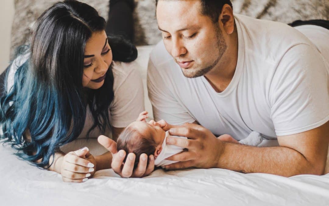 Two parents looking over their newborn with serious expressions on their faces.