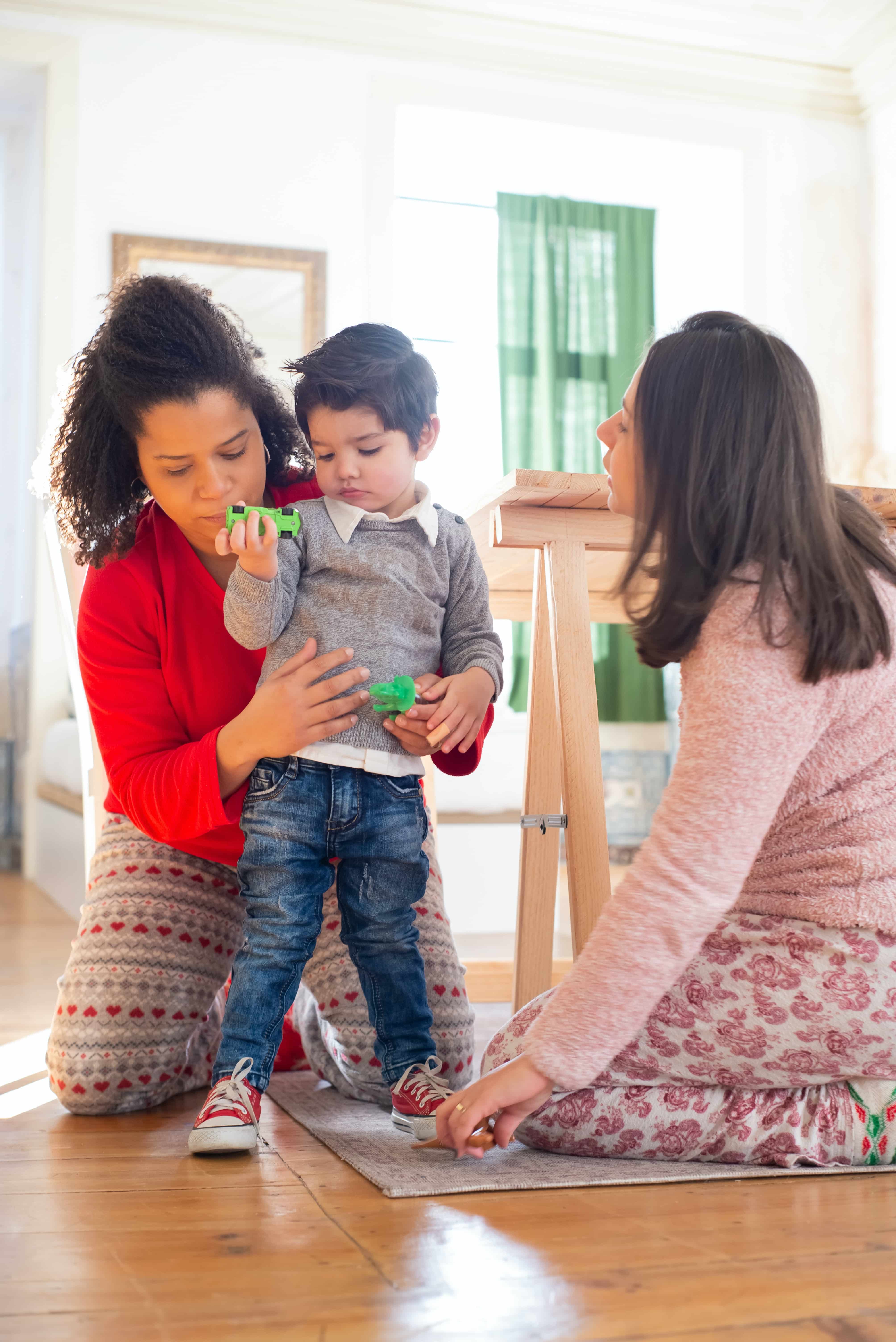 Gay mom couple in pajamas, playing with their child in their San Francisco home.  