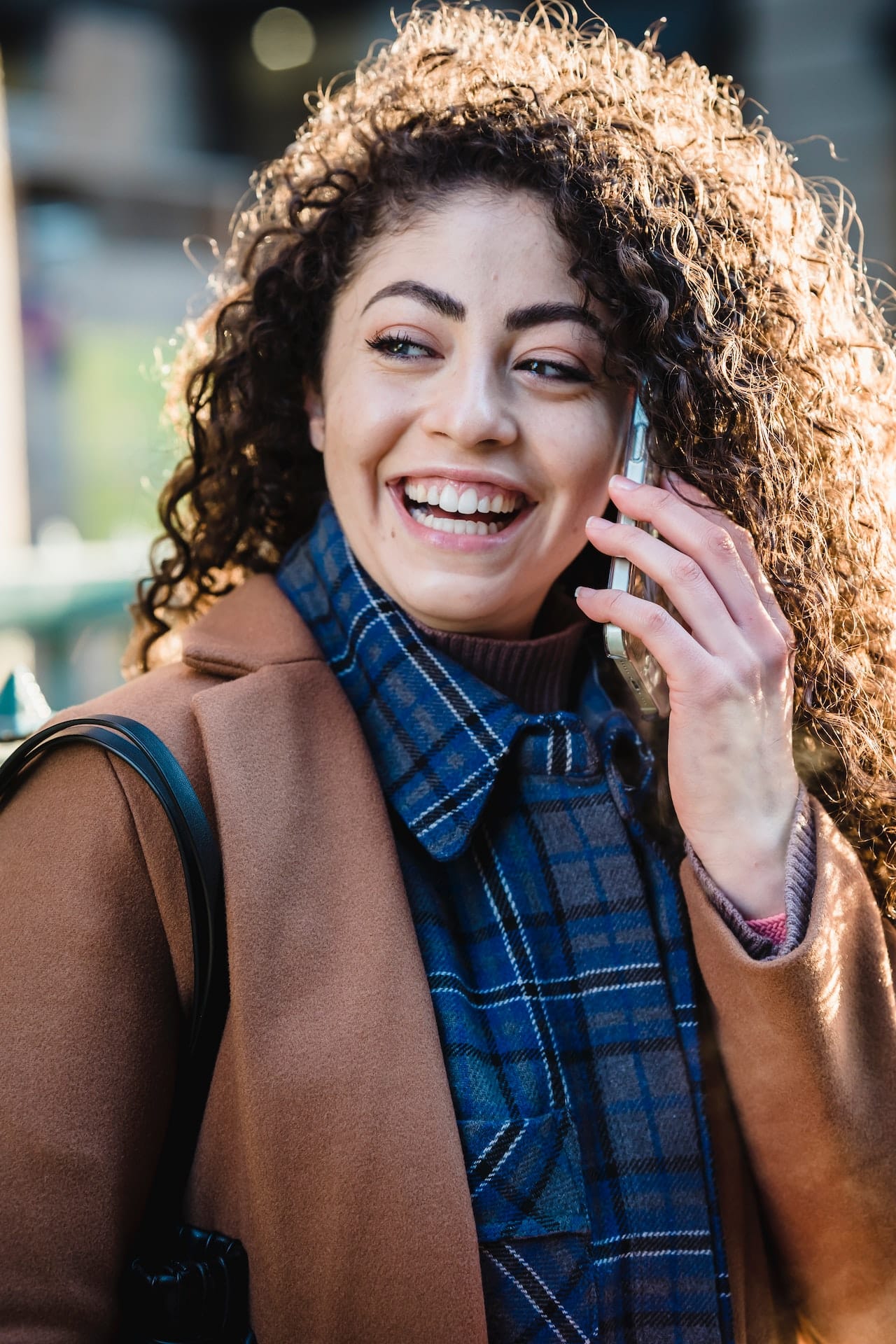 A happy Latina woman talking on her cell phone with a smile on her face