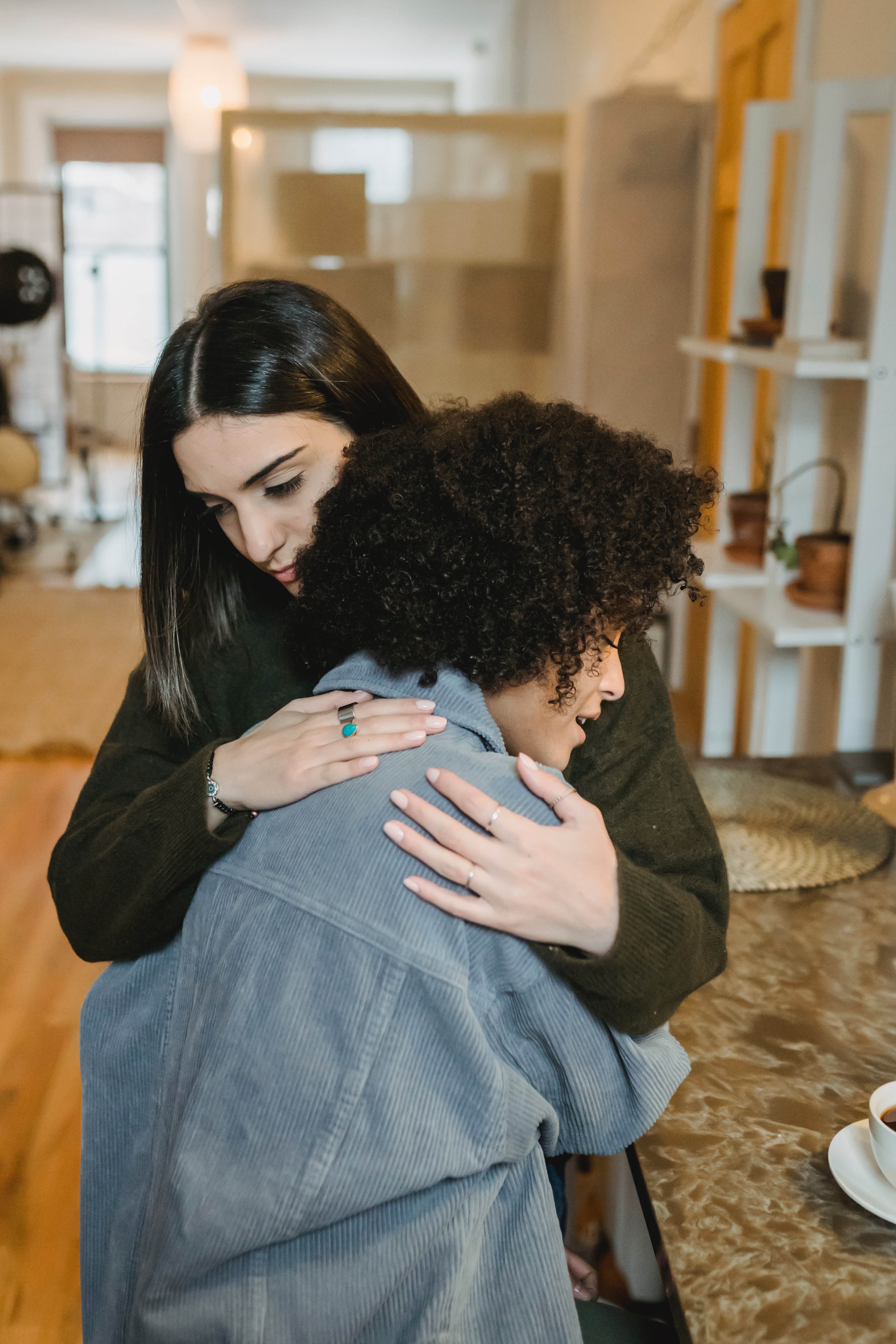 Two women embracing with serious expressions. 