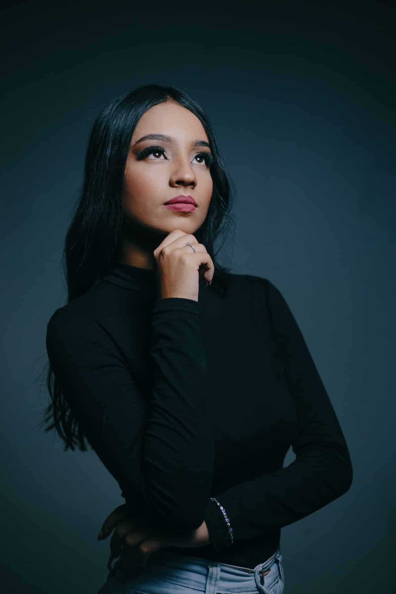 A Latina woman in a black top poses with a serious expression on her face