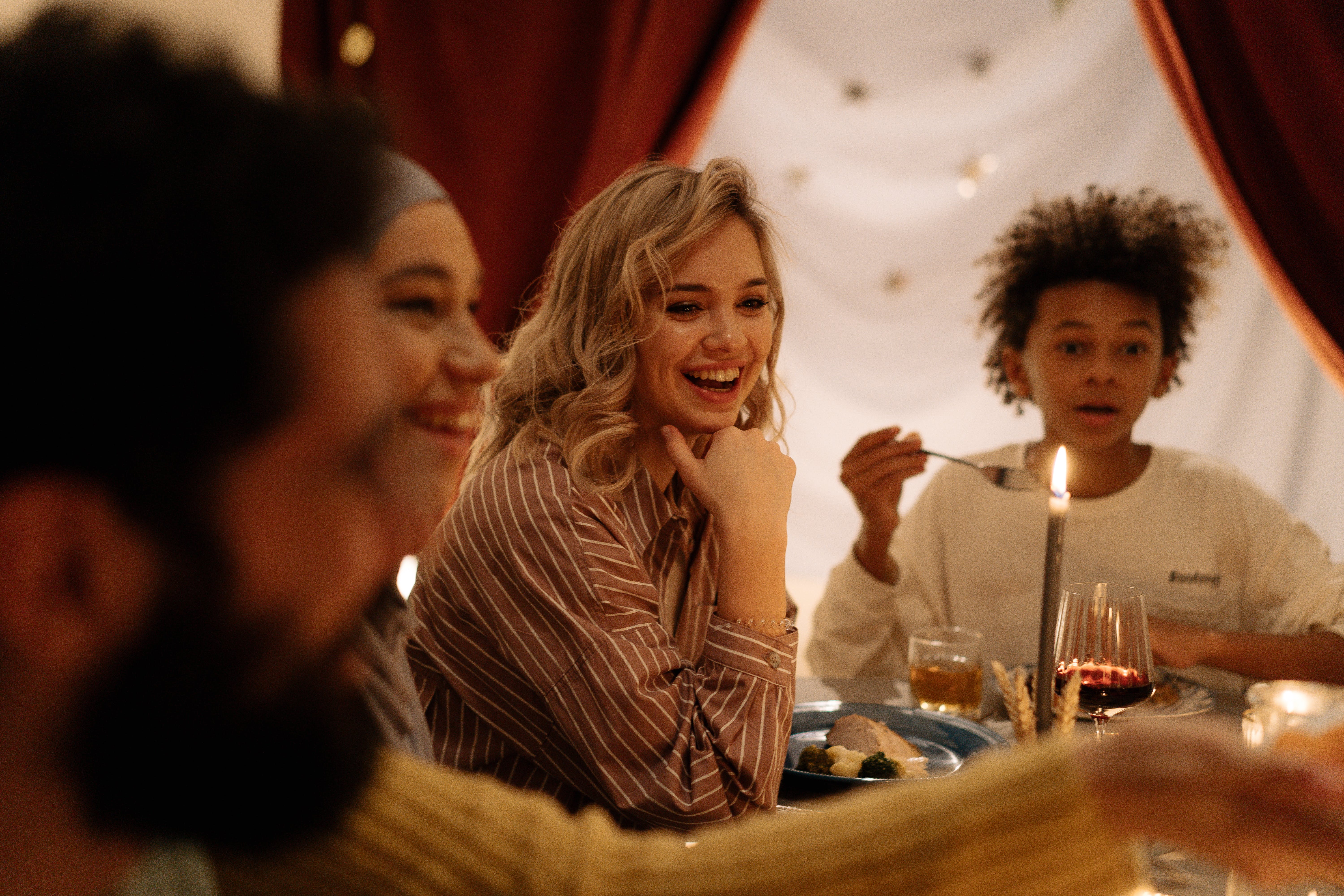 A group of friends smiling and sitting next to each other at a fully set table. 