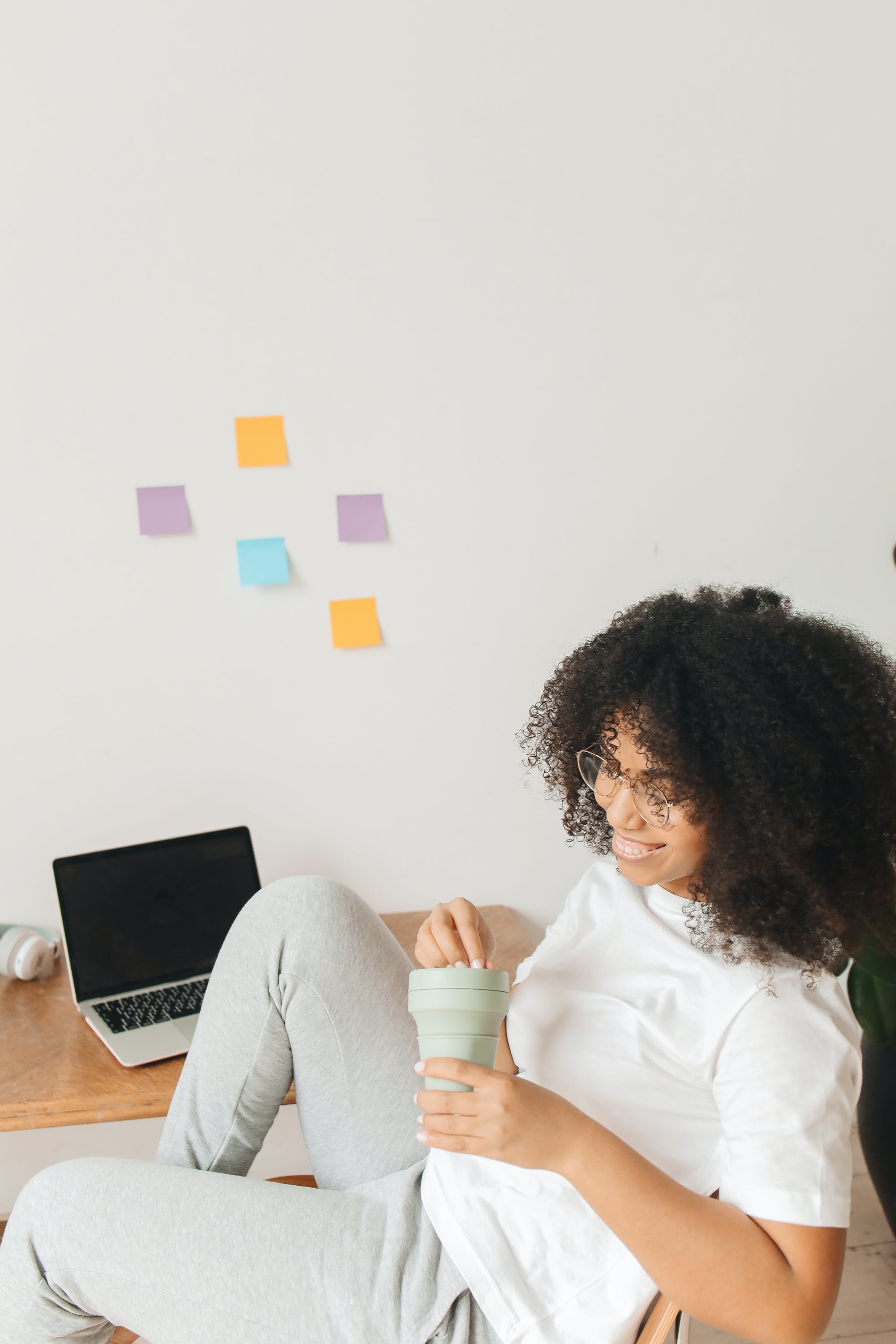 A Black woman smiling, turned away from an off computer