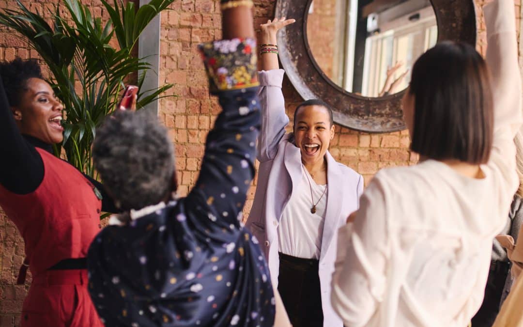 A group of young Black women raising their hands to high five/celebrate one another