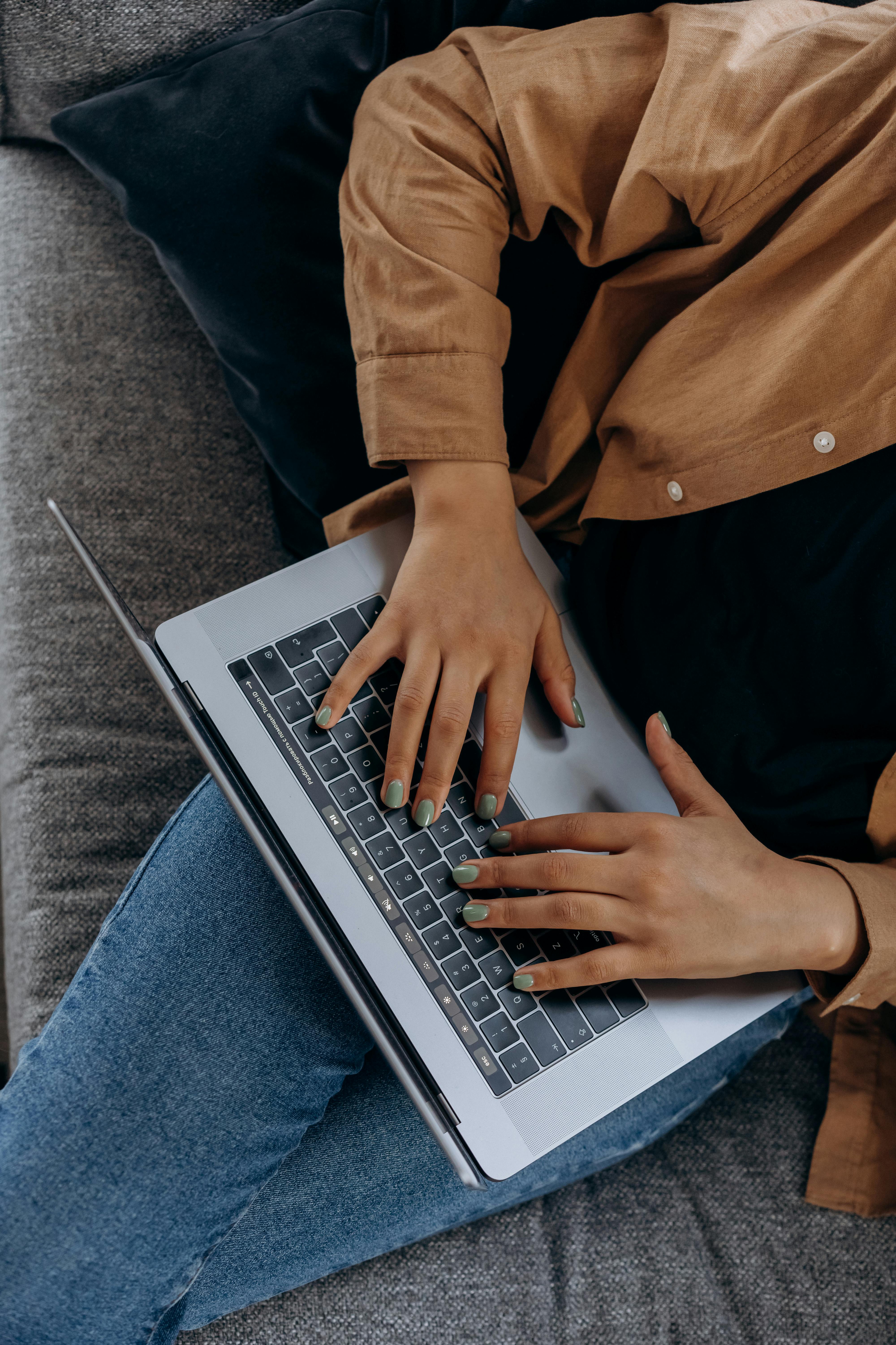 A photo from above of a person's lap with hands typing on a laptop
