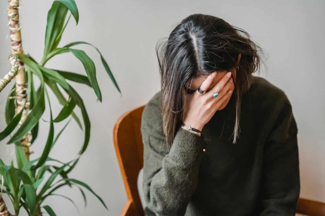 A woman within short black hair, experiencing a headache.