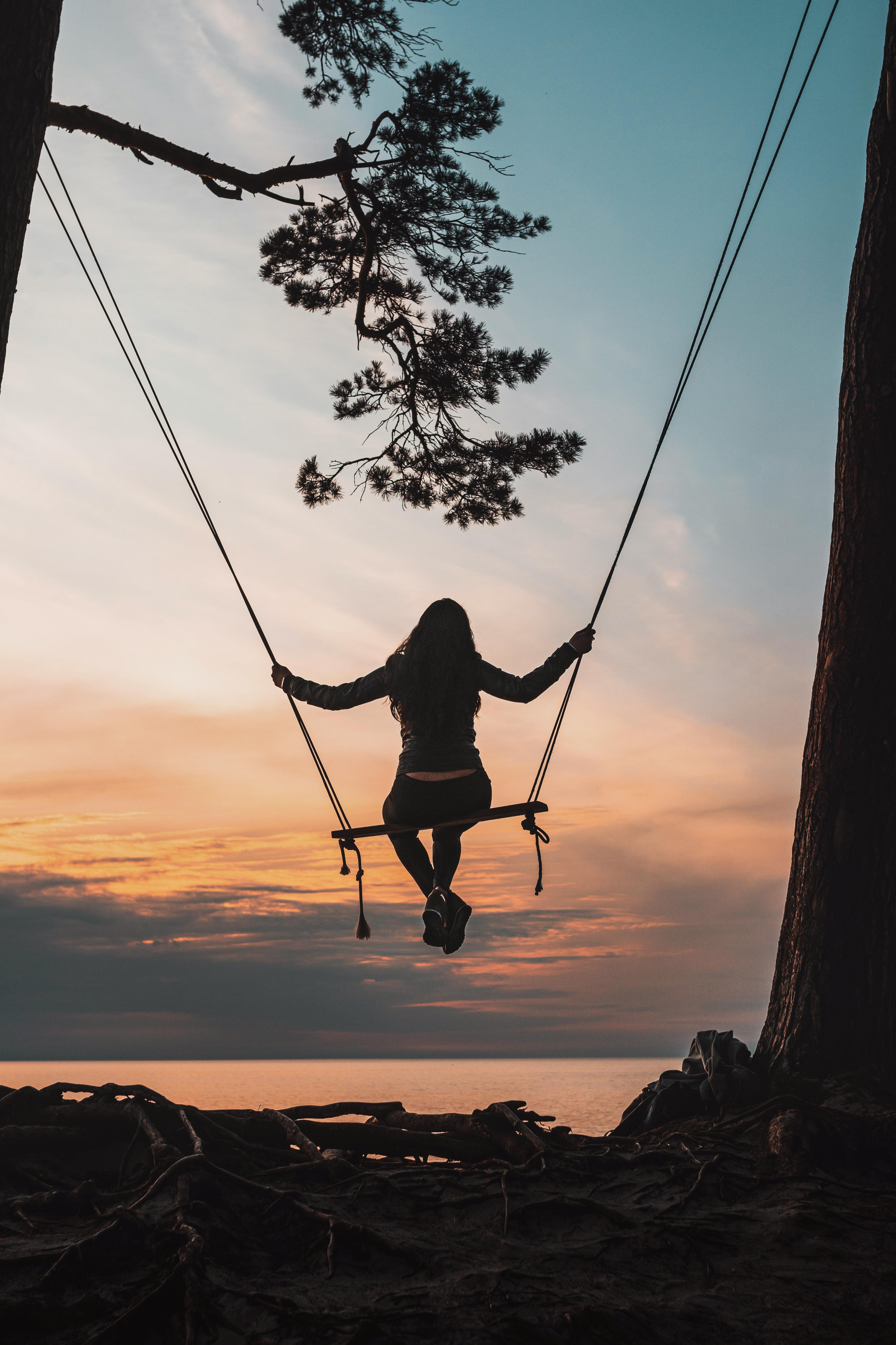 Silhouette of a woman on a swing against a beautiful sky
